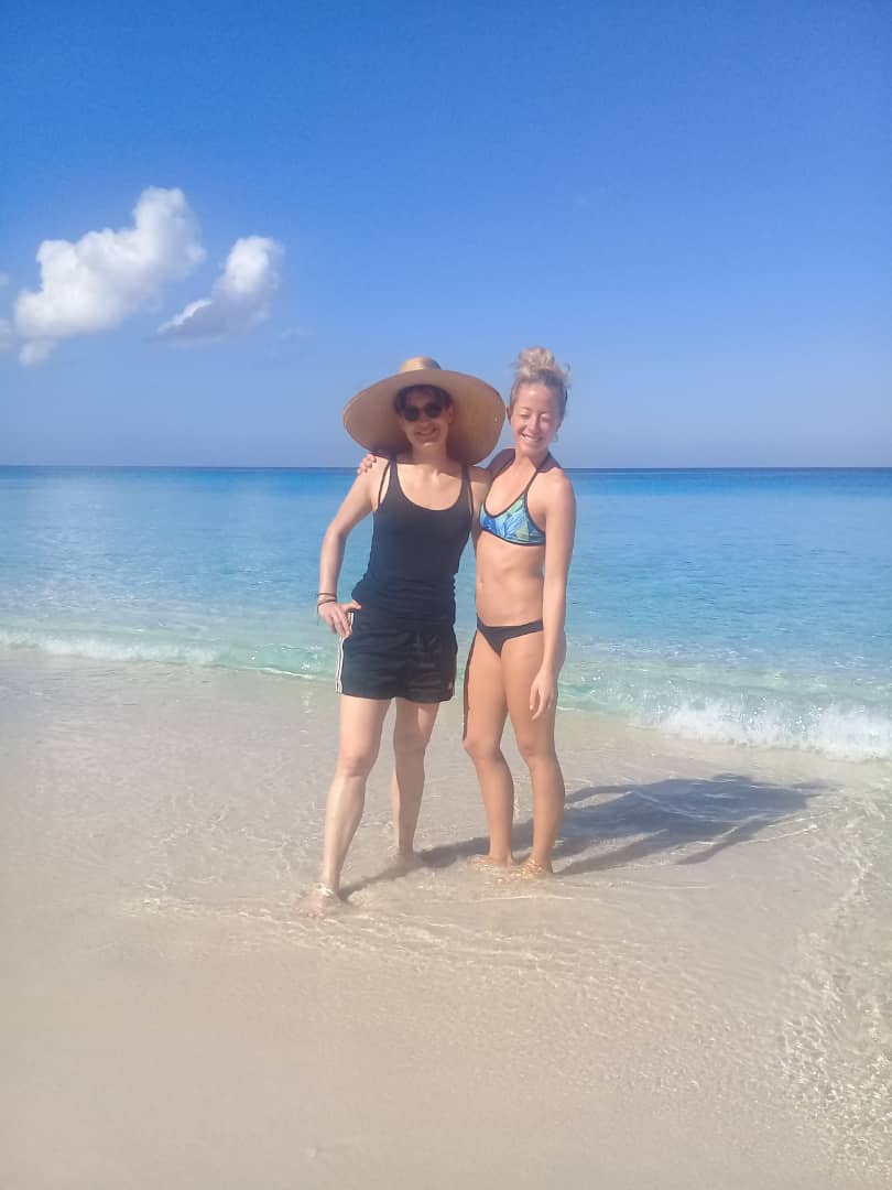 two women close to each other smilling on the beach